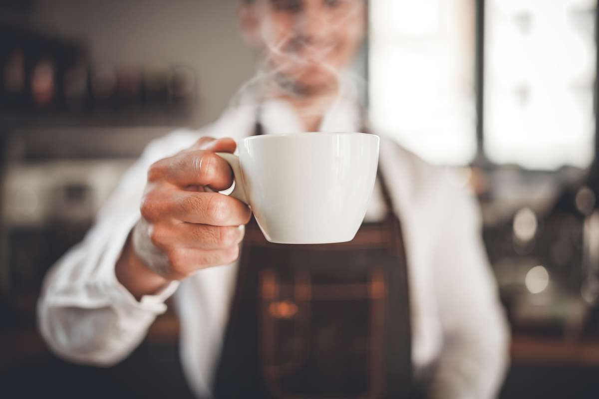 Personne tenant une tasse de café fumant