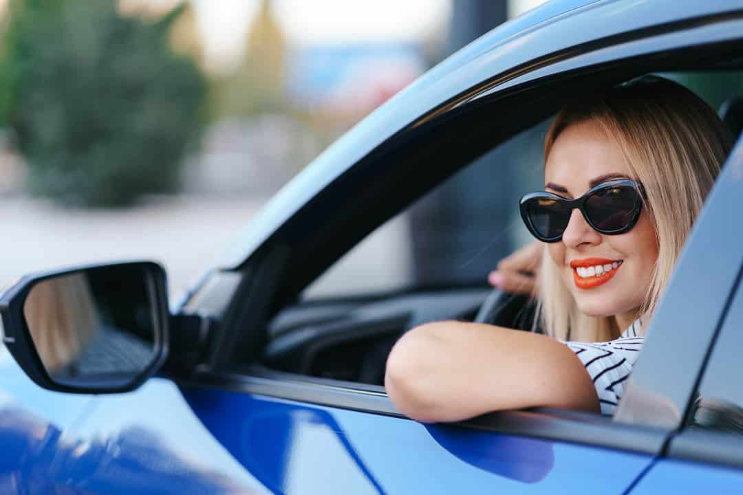 Jeune femme souriante conduisant une voiture