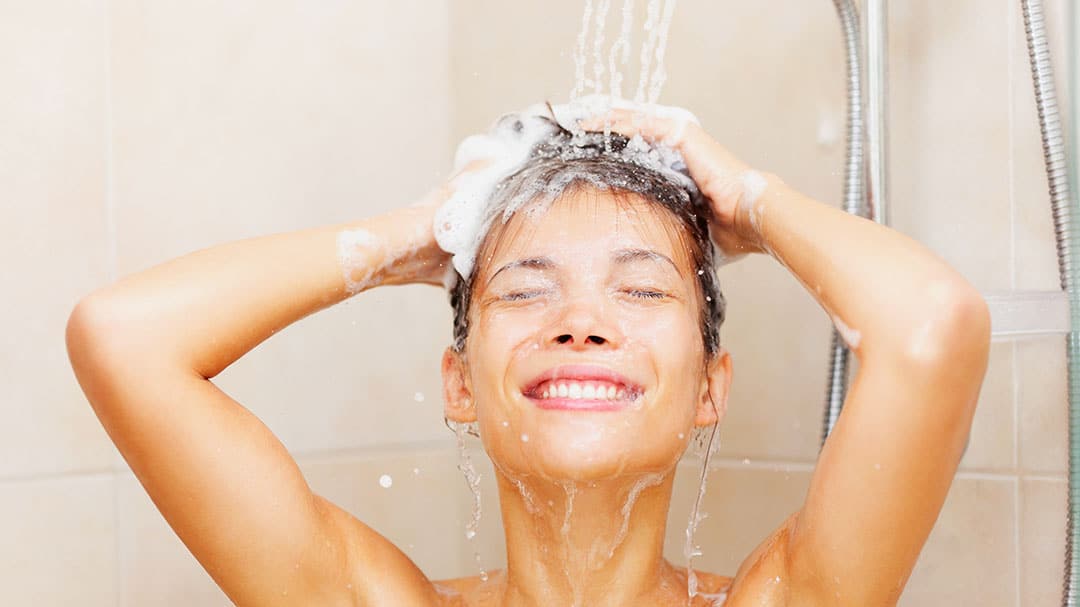 Femme souriante se lavant les cheveux sous la douche