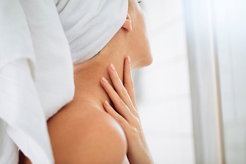 femme touchant son cou avec une expression inquiète