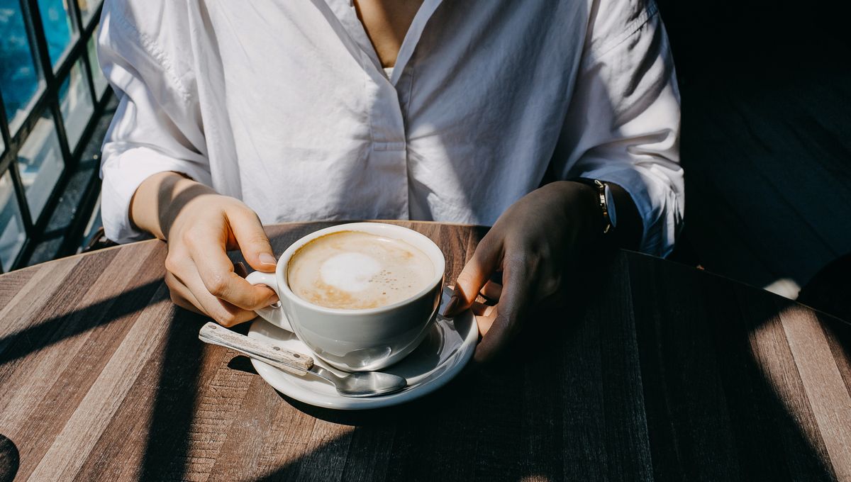 Personne versant du lait dans un café