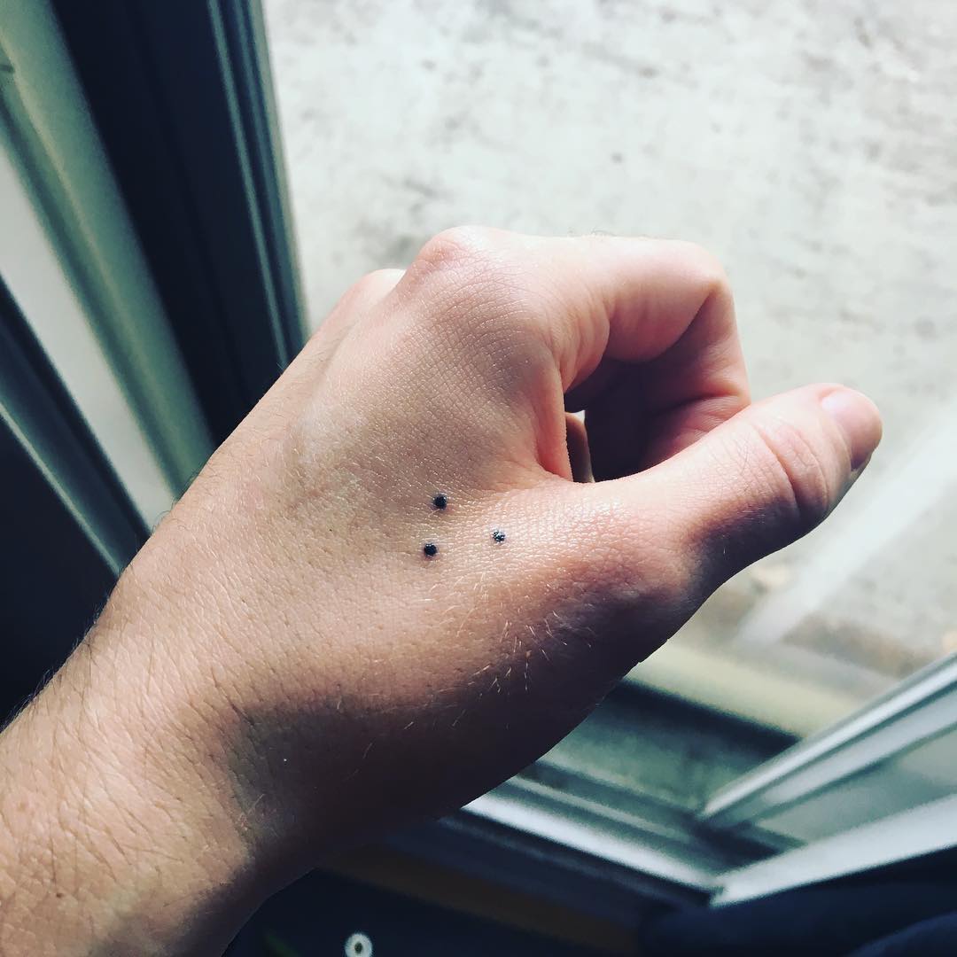 Tatouage minimaliste à trois points sur la main