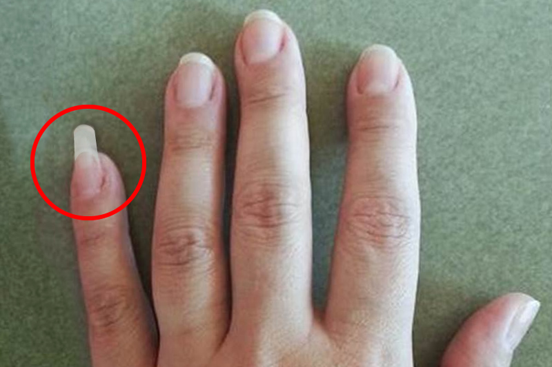 Personne utilisant son ongle long de l'auriculaire comme un outil pratique au quotidien