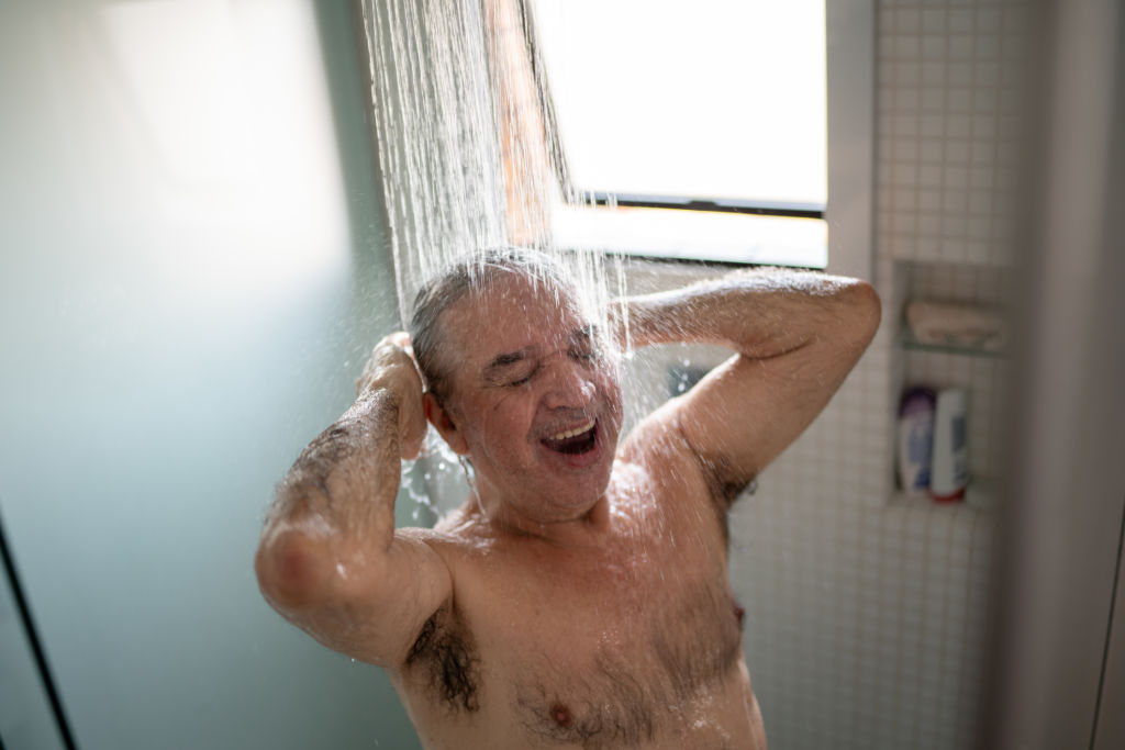 Homme âgé heureux prenant une douche à domicile