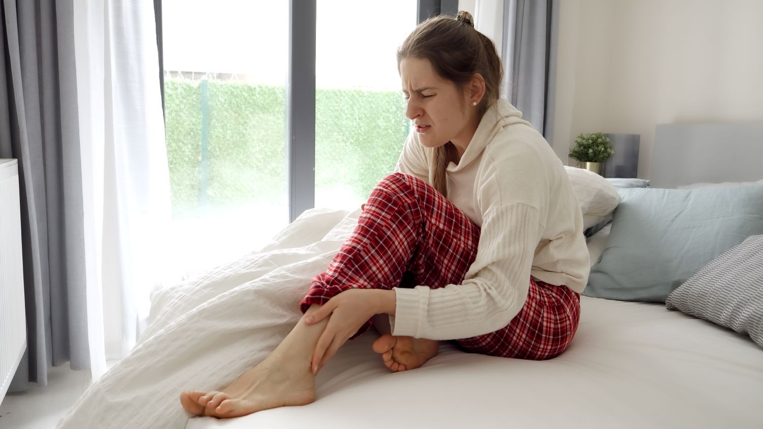 Femme ressentant des crampes nocturnes aux jambes