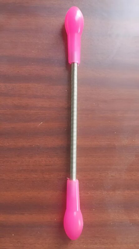 Ressort métallique rose tenu entre les doigts