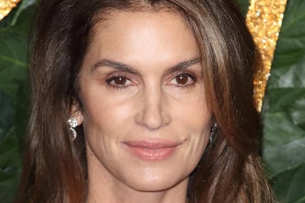 Cindy Crawford souriante, arborant des cheveux argentés avec naturel et élégance
