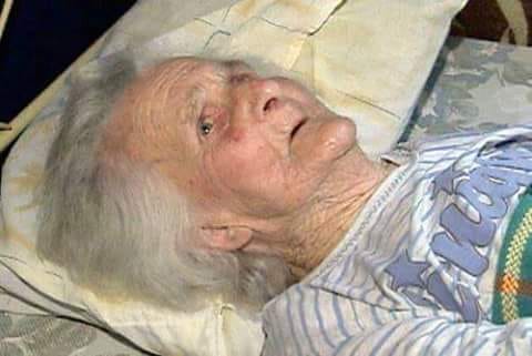 Détail de mains âgées et jeunes entrelacées sur un lit