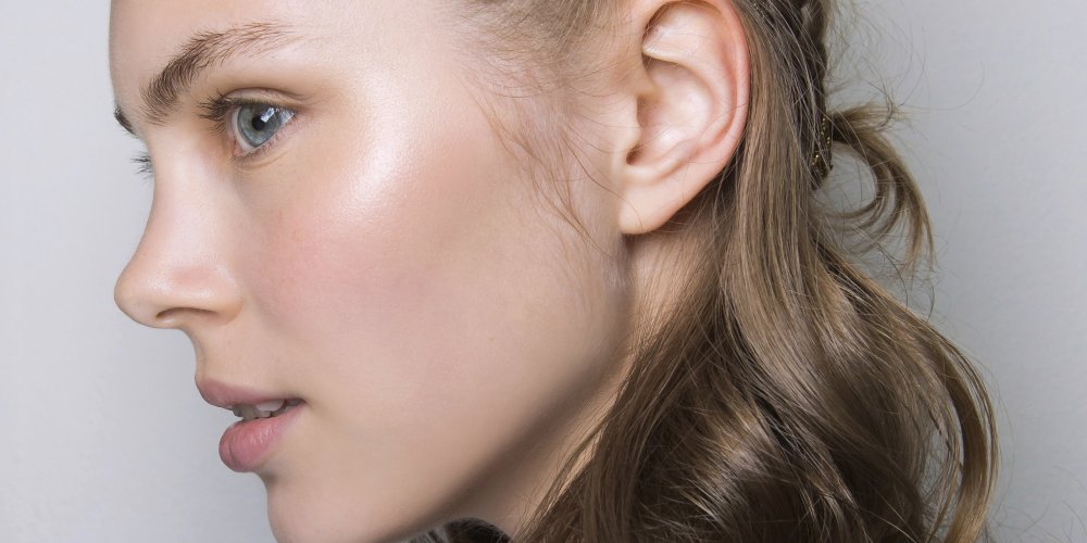 Femme appliquant un soin maison sur son visage, près d'une fenêtre lumineuse