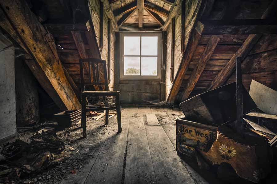 Intérieur d'un grenier ancien avec des objets recouverts de poussière et une lumière tamisée