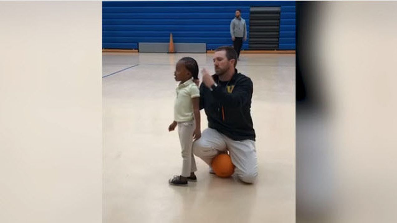 Entraîneur agenouillé attachant les cheveux d'une jeune joueuse de basket