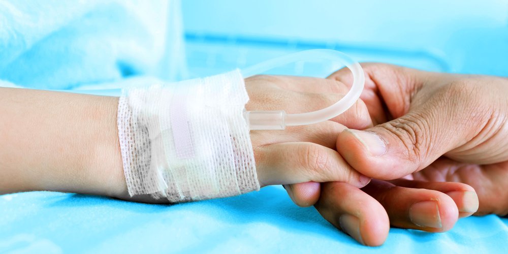 Main d'un adulte tenant doucement la main d'un enfant à l'hôpital