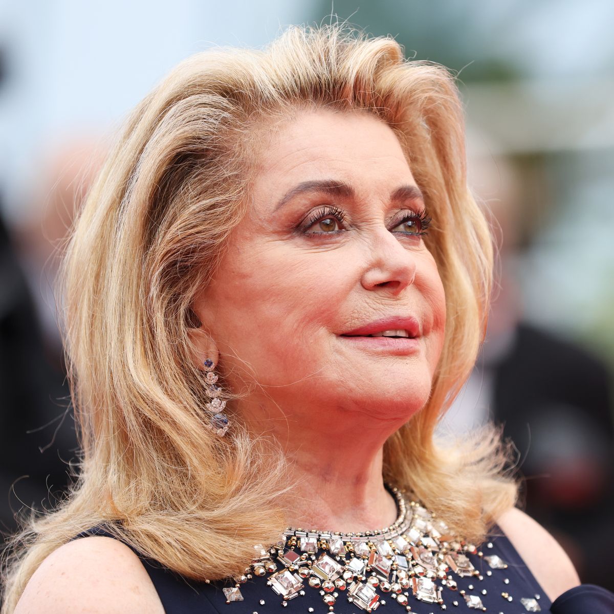 Portrait de Catherine Deneuve mettant en avant sa peau lumineuse et son style intemporel