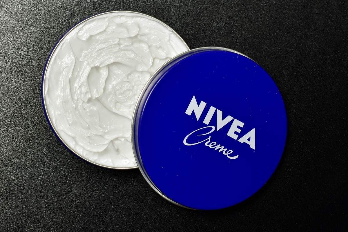 Pot bleu de crème Nivea entouré de fleurs et d'ingrédients naturels